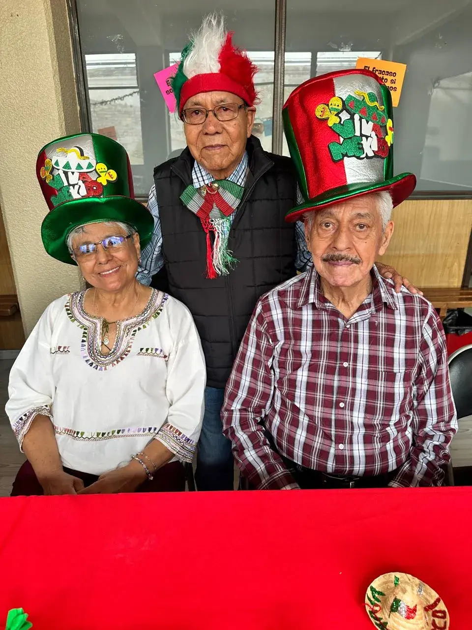 Trío de integrantes del Centro AM con sombreros patrios durante un festejo mexicano