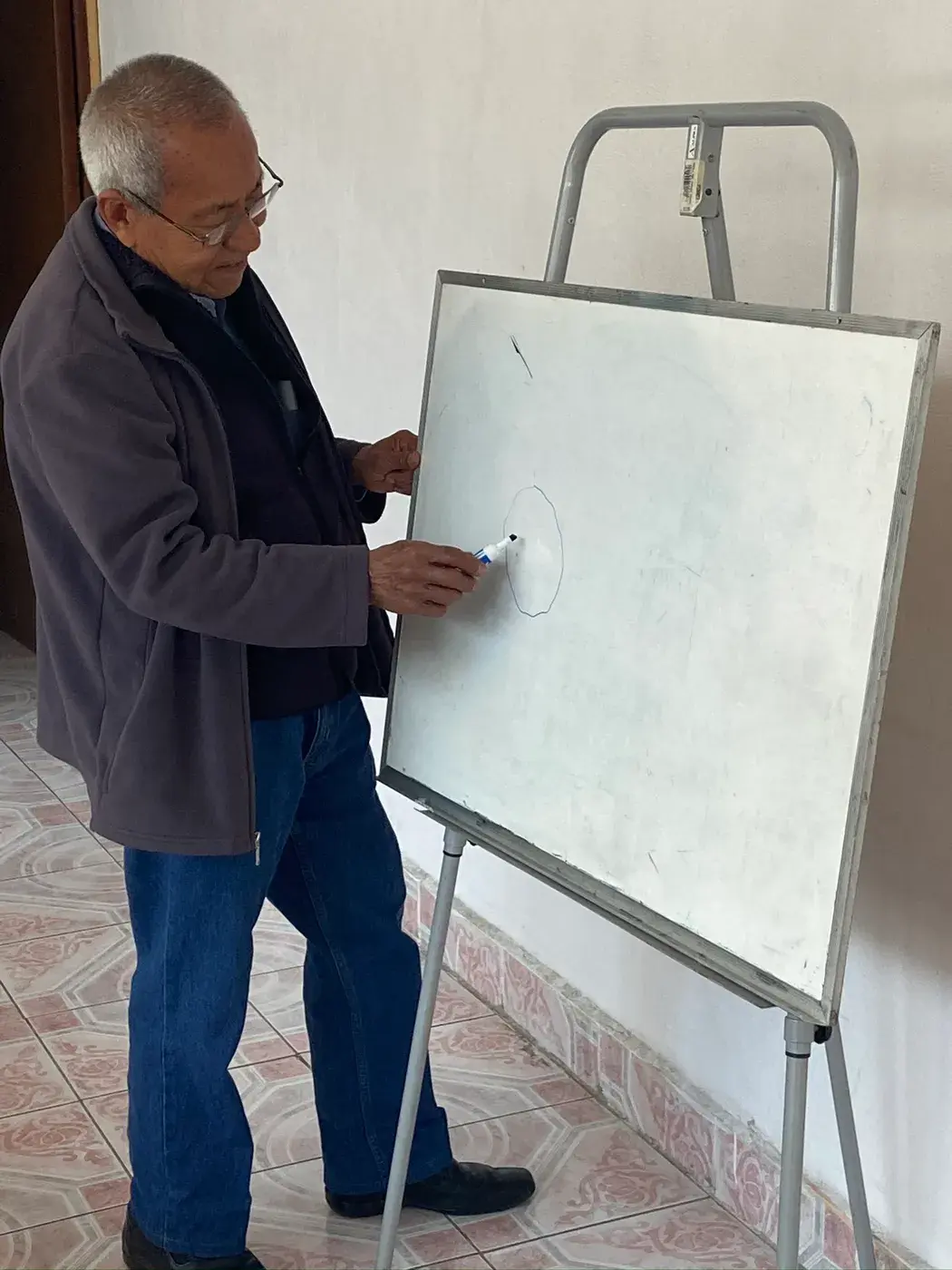 Participante del Centro AM escribiendo en el pizarrón durante una actividad educativa