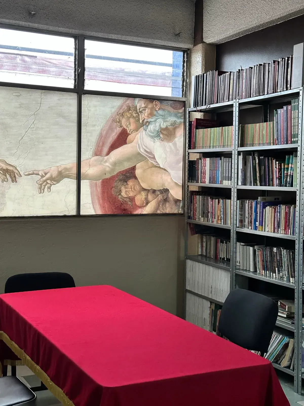 Biblioteca de CADE con estanterías y mural artístico