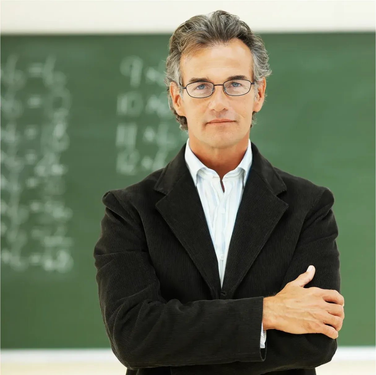 Docente con lentes y brazos cruzados frente a un pizarrón