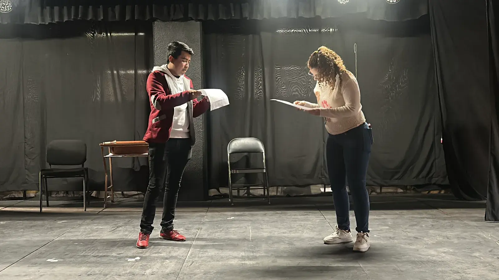 Dos actores ensayando con guion bajo luz cenital